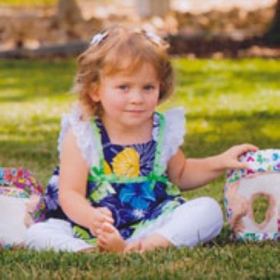 Children's Hospital Colorado spine surgery patient Nora sits on the grass in a park.