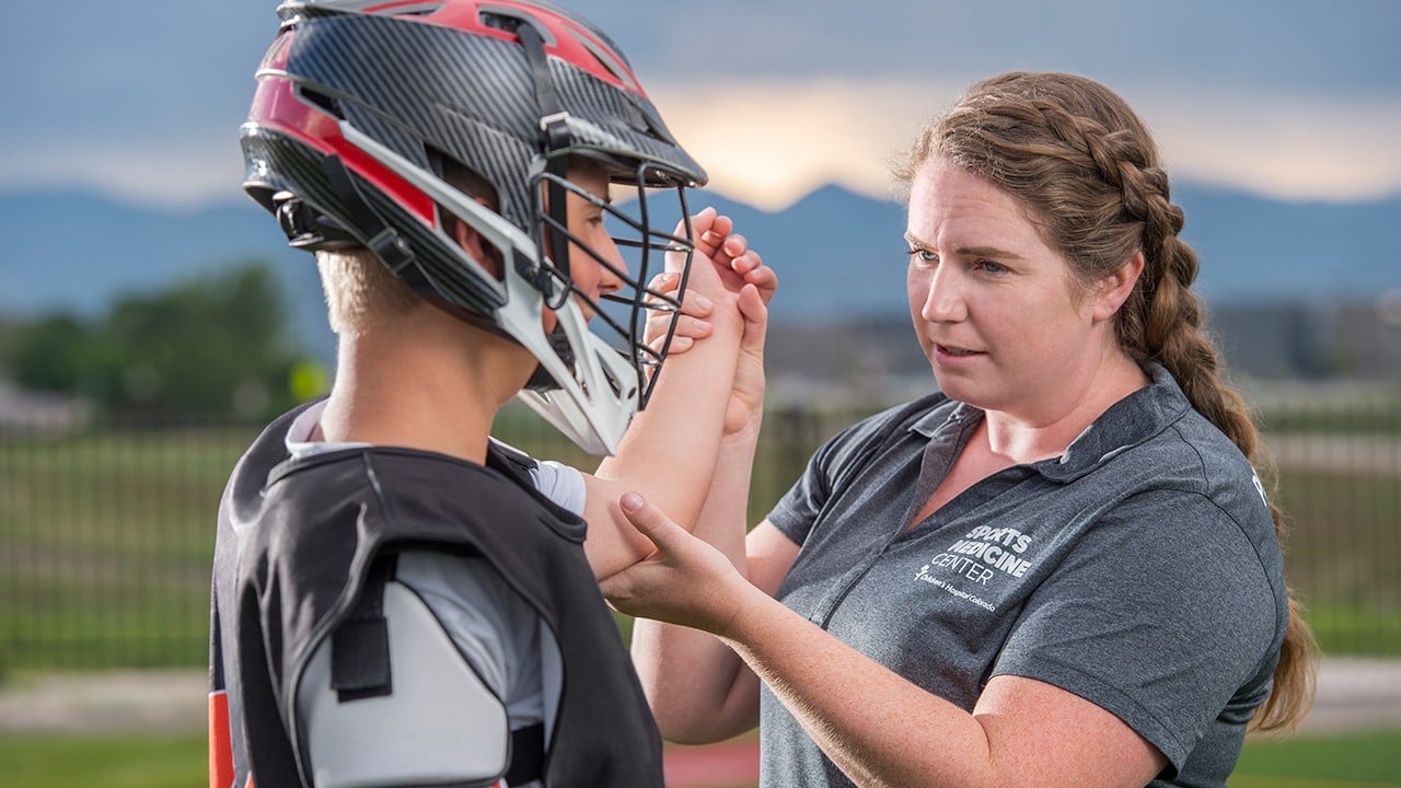Athletic trainer checks lacrosse player's elbow.